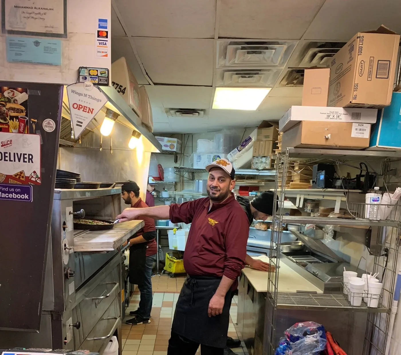 Team member pulling a pizza from the oven, seen across the front counter
